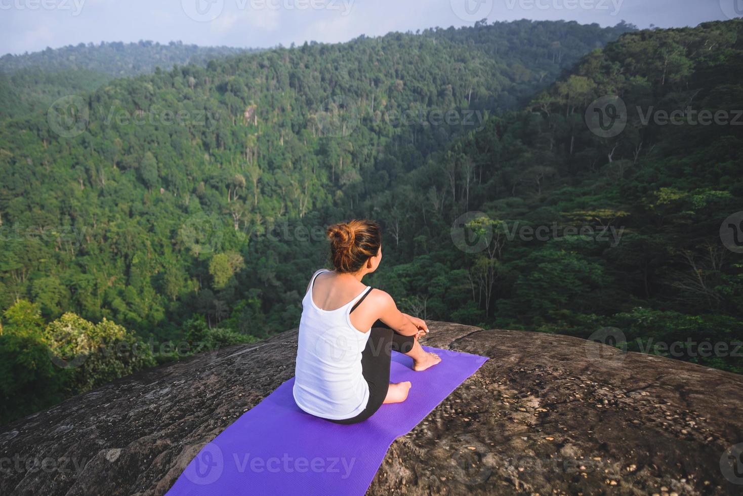 Asian women relax in the holiday. Play if yoga. On the Moutain rock cliff. Nature of mountain forests in Thailand. Young woman practicing yoga in the nature female happiness. exercise yoga photo