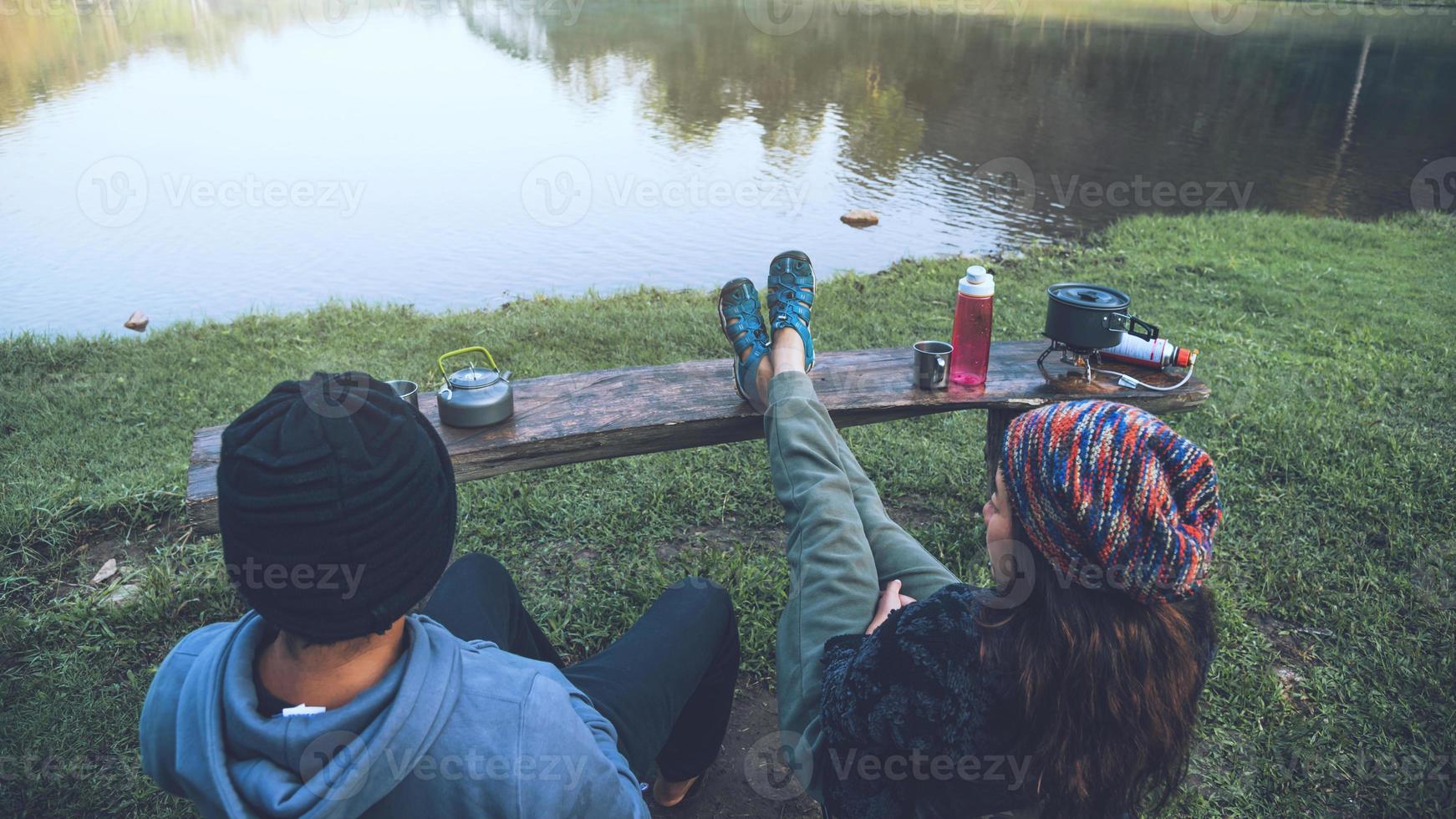 Las parejas asiáticas se sienten relajadas y felices tomando café por la mañana junto al lago. pareja romantica viajando acampar, luna de miel. foto