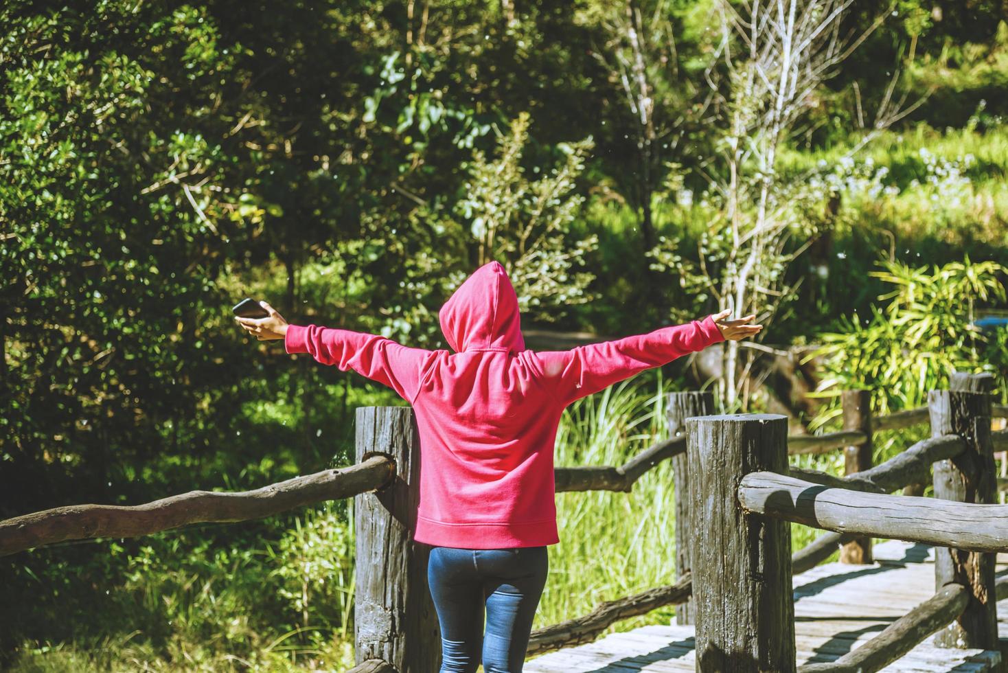 La naturaleza de los viajes de la mujer joven está caminando hacia adelante en la dirección del puente de madera. foto