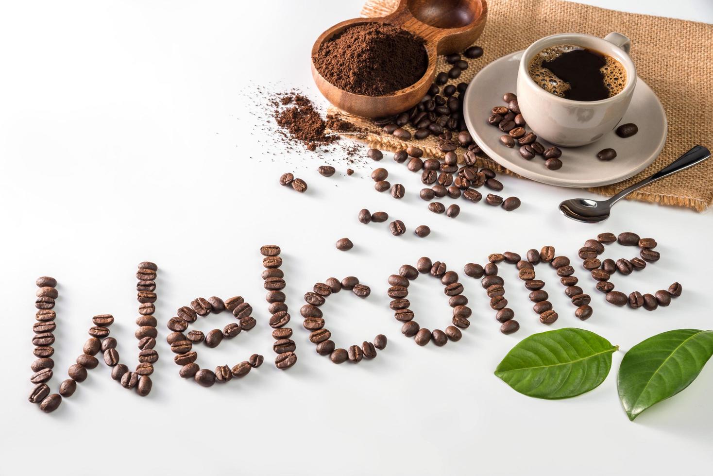 taza de café y texto de granos de café, aislado en blanco. envía un mensaje de texto a la palabra bienvenida hecha de granos de café. fuente foto