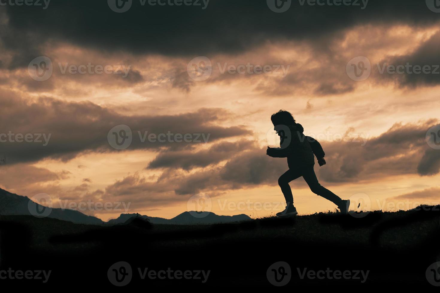 Child in silhouette while running photo