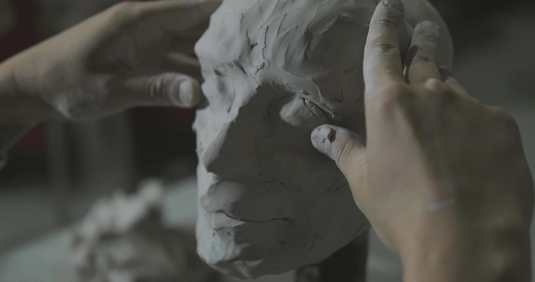 Sculptor work with clay portrait of female in dark studio UHD4K photo