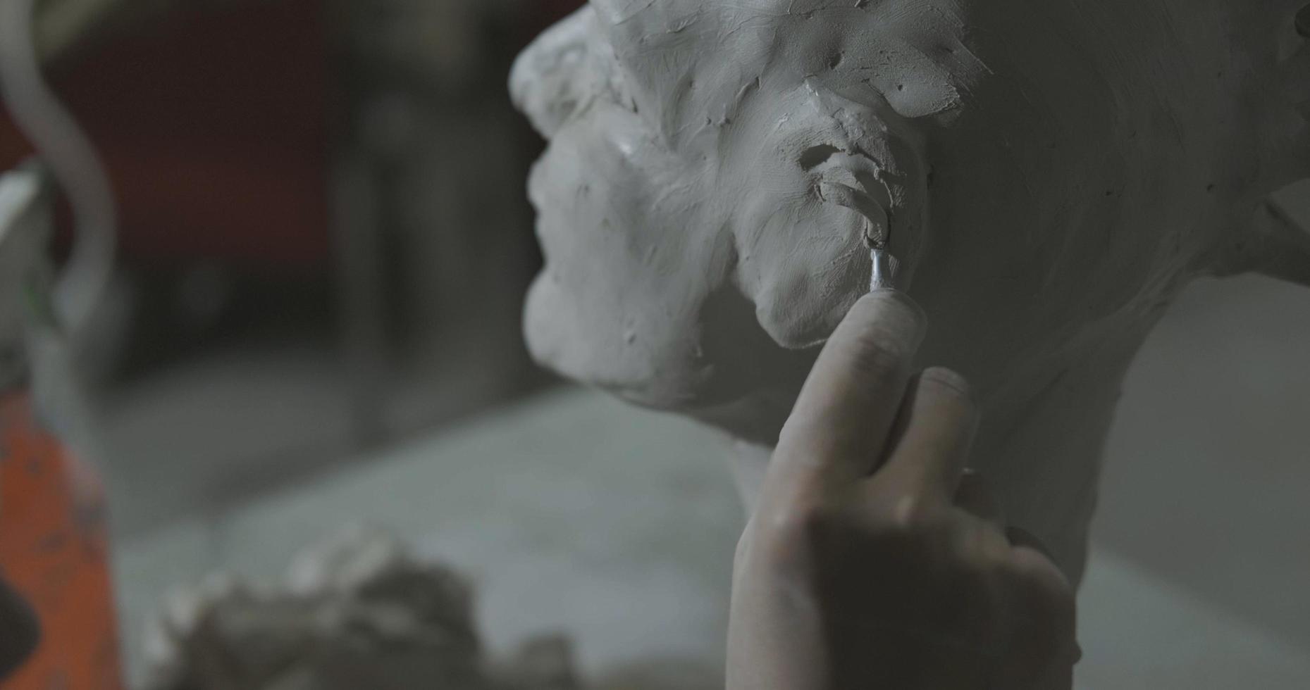 Sculptor work with clay portrait of female in dark studio UHD4K photo