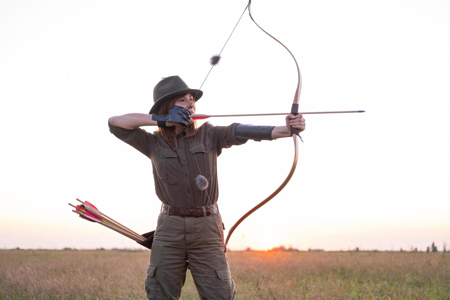 mujer con arco al aire libre en el campo foto