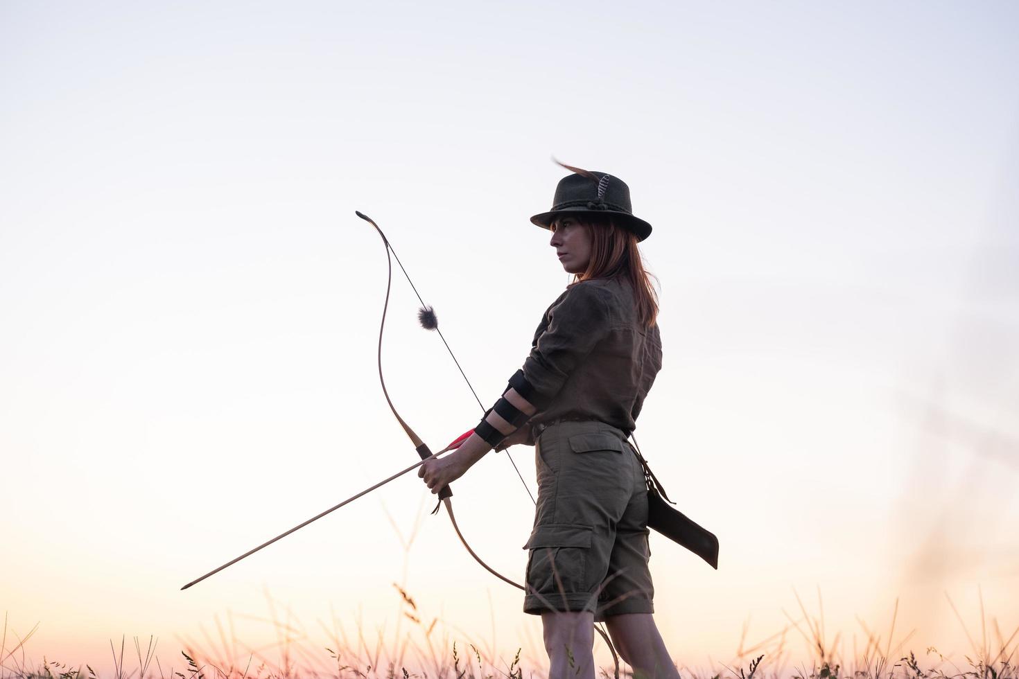 mujer con arco al aire libre en el campo foto