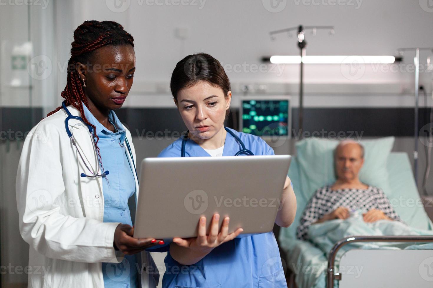 doctor and nurse using laptop in hospital room photo