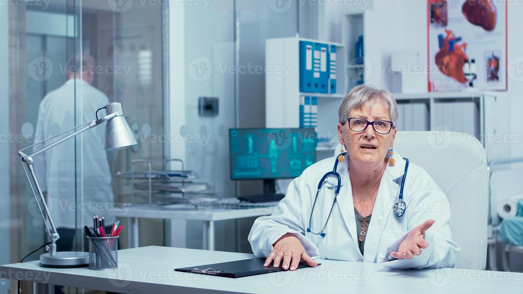 Authentic experienced old woman doctor talking to the camera photo