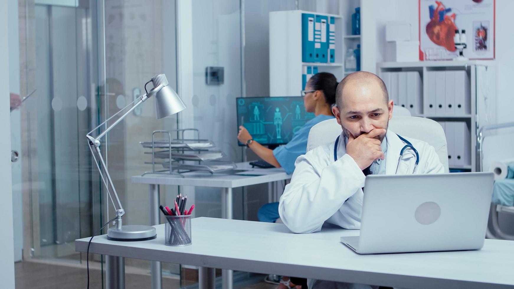 Man doctor typing on laptop in modern office photo