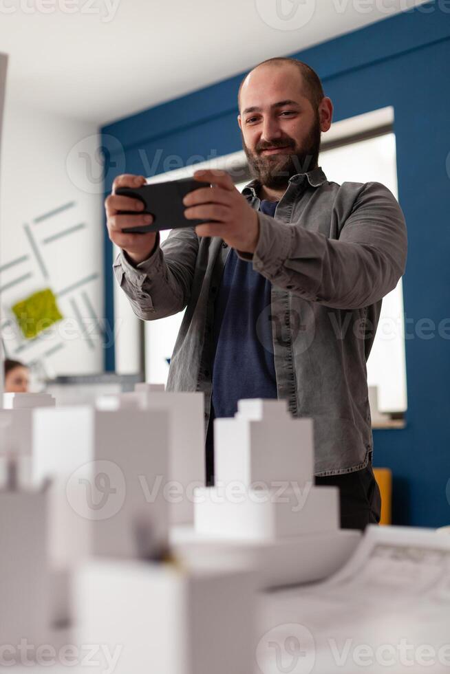 Expert architect looking on smartphone at workplace photo