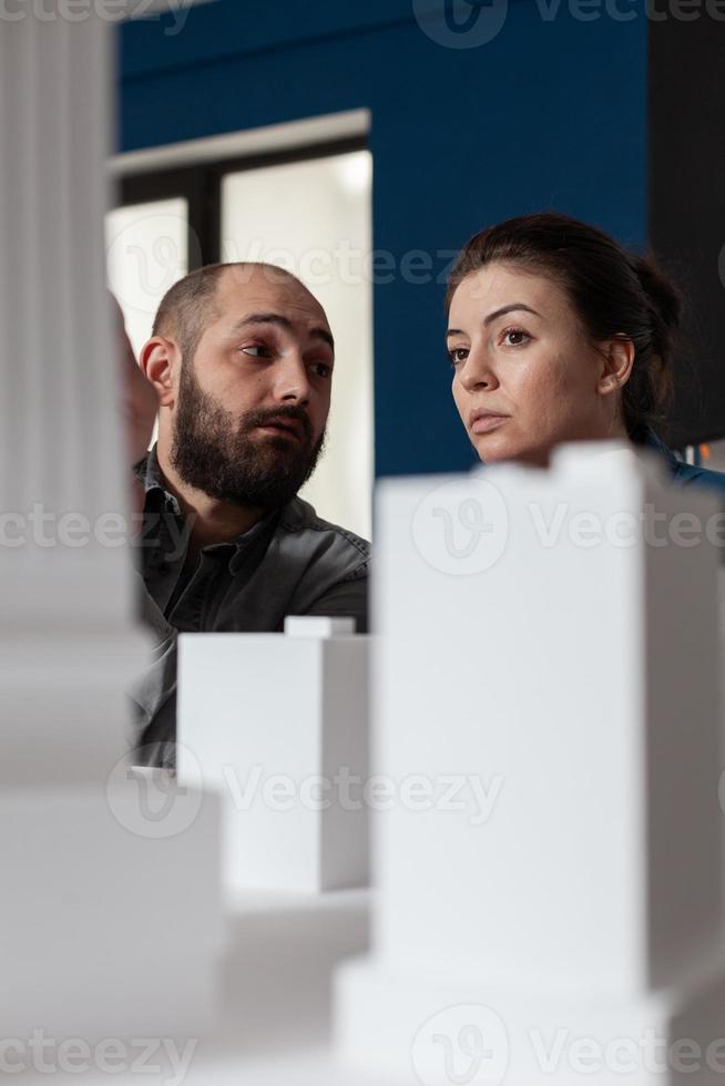 Hablando del equipo de arquitectos sentados frente al escritorio en la oficina profesional foto