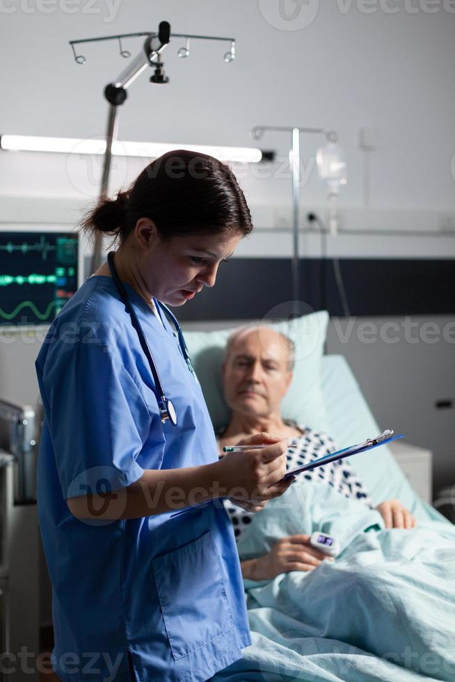 Medical nurse in scrubs taking notest on cliboard photo