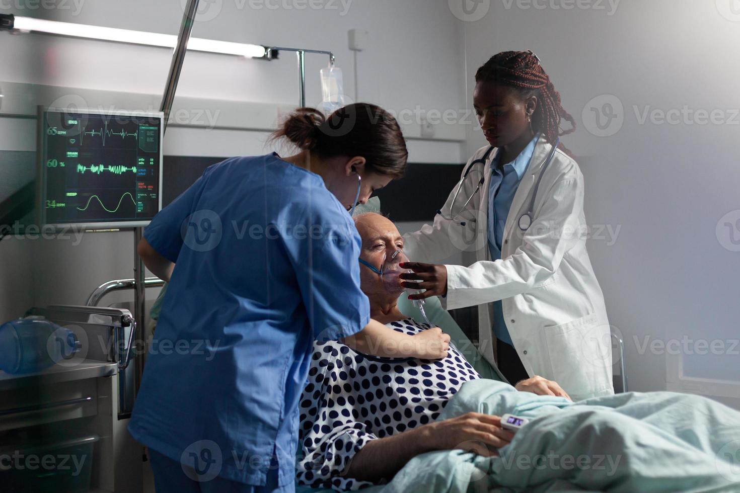 Médico africano ayudando a la respiración del paciente mayor utilizando un tubo de ventilación repiratoria foto