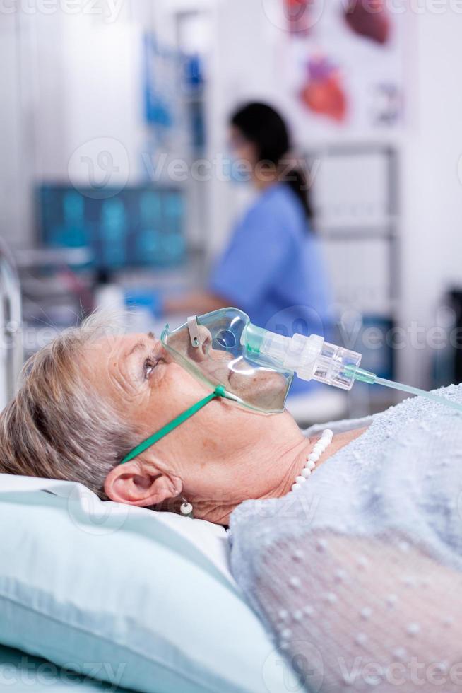 Oxygen mask helping old woman breath photo