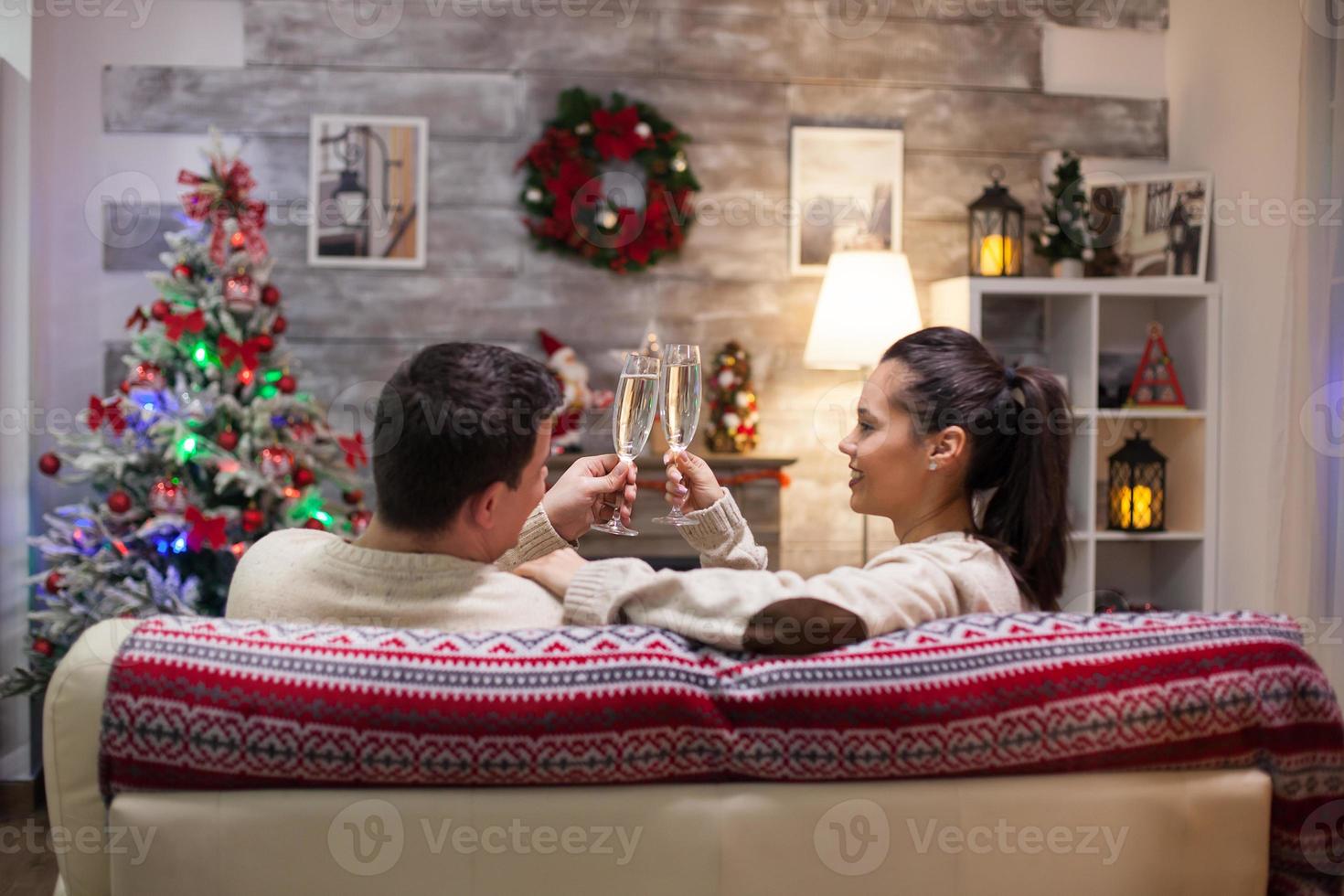 Back view of couple in matching clothes clinking a glass of champagne photo