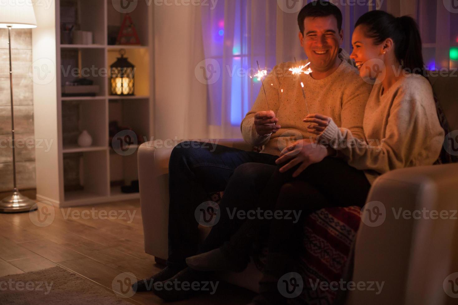 pareja riendo mientras sostiene luces de bengala foto