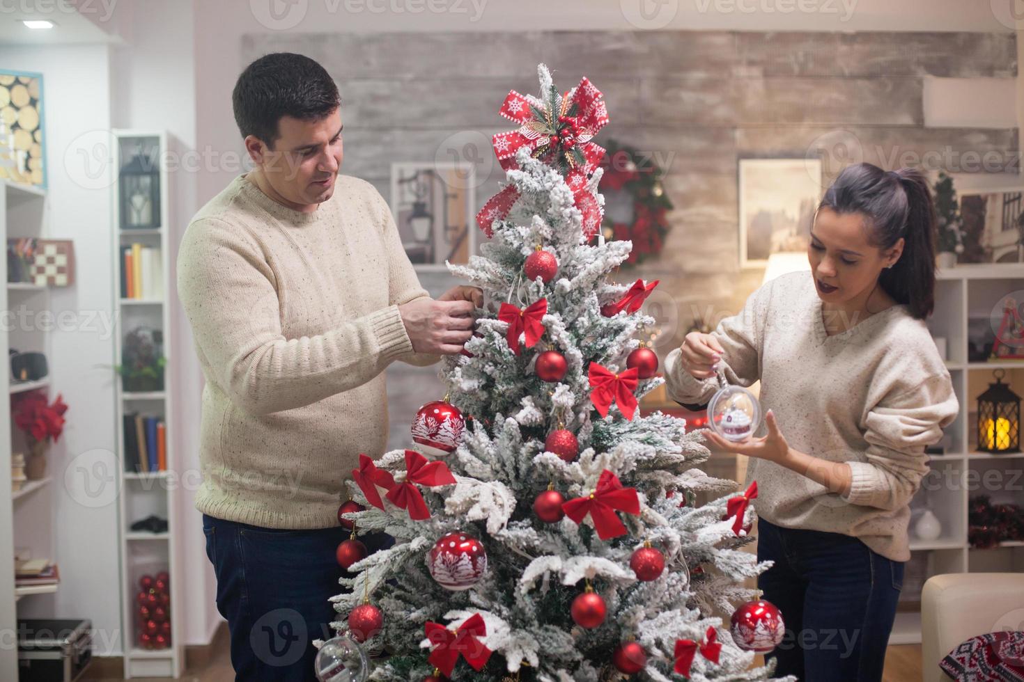 apuesto joven y su novia preparando su árbol de navidad foto