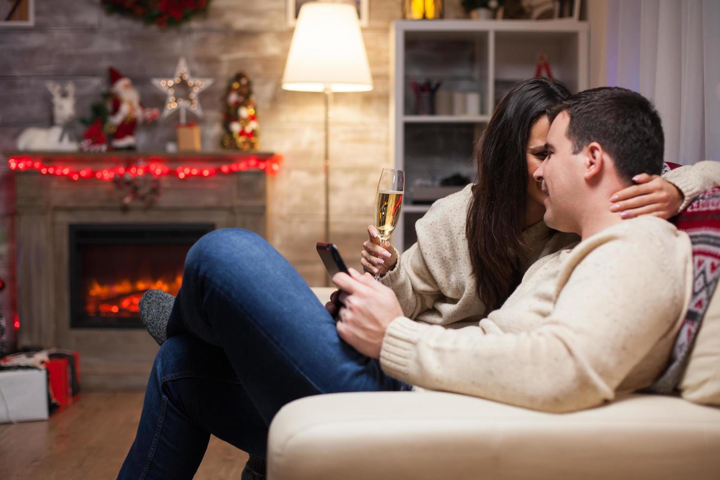 Beautiful woman holding a glass of wine and whispering something to her husband photo