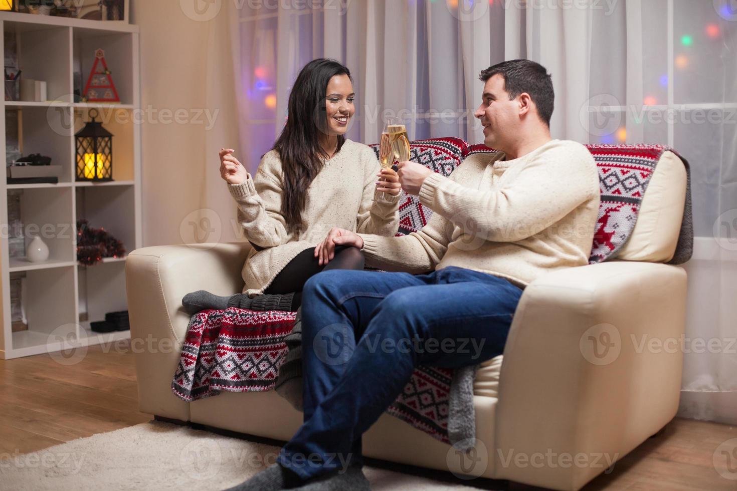 Hermosa joven pareja celebrando la Navidad sentado en el sofá foto