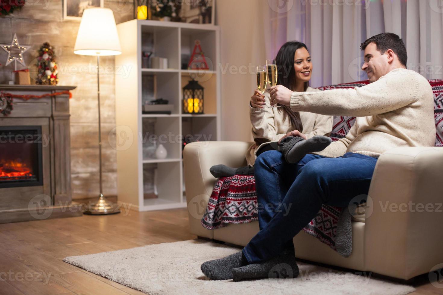 Pareja de enamorados sentados en el sofá celebrando la Navidad foto