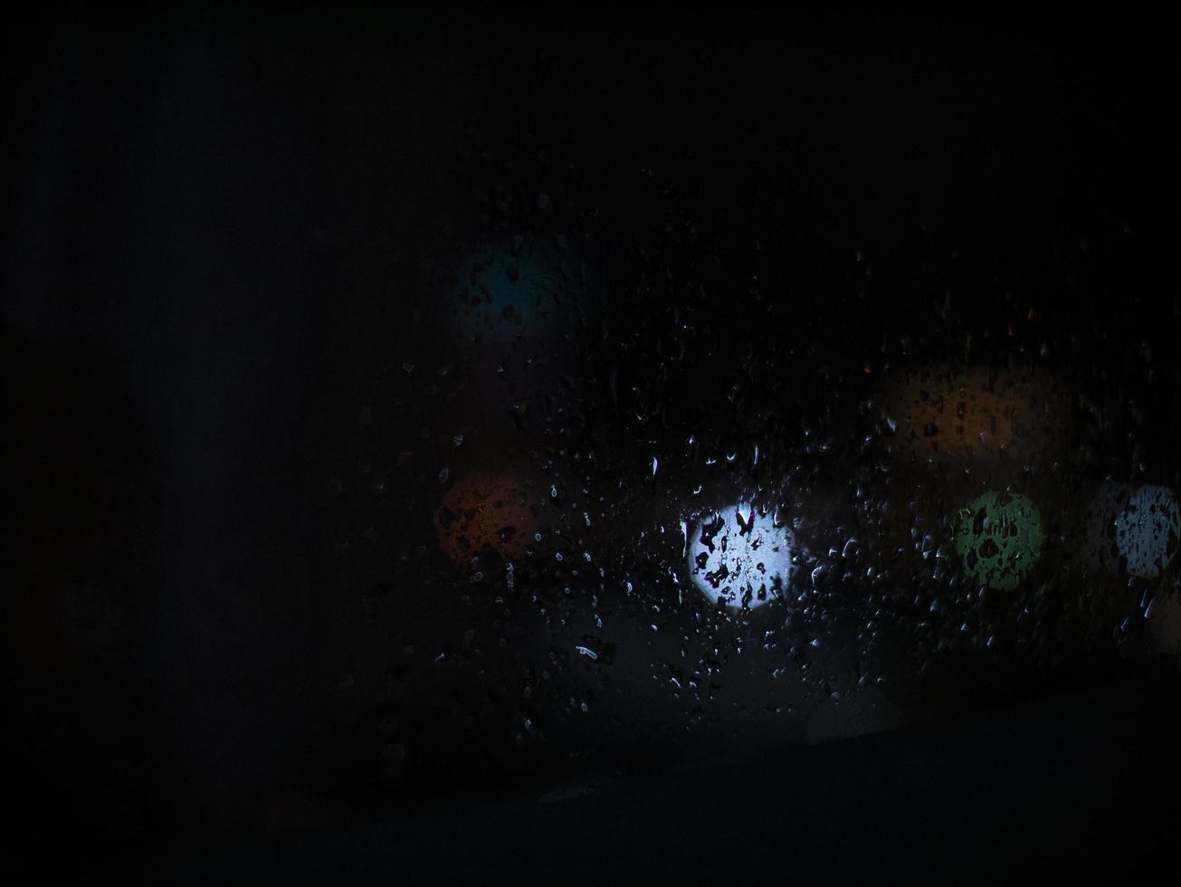 gotas de lluvia sobre el vidrio en el fondo de la noche foto