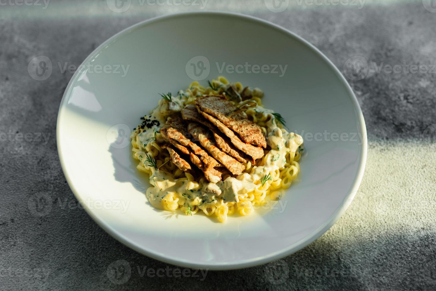 plato con trozos de carne, pasta, verduras, salsa de foie gras foto