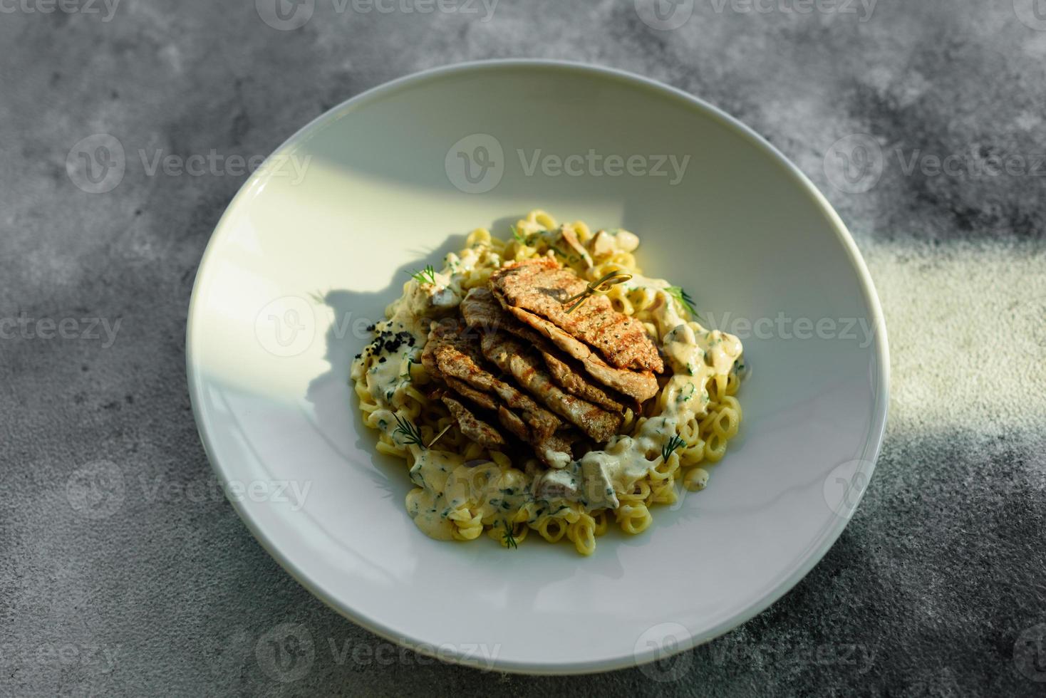 Dish with meat pieces, pasta, greens, sauce from a foie gras photo