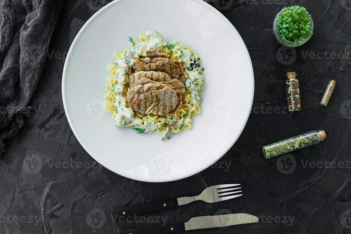 plato con trozos de carne, pasta, verduras, salsa de foie gras foto