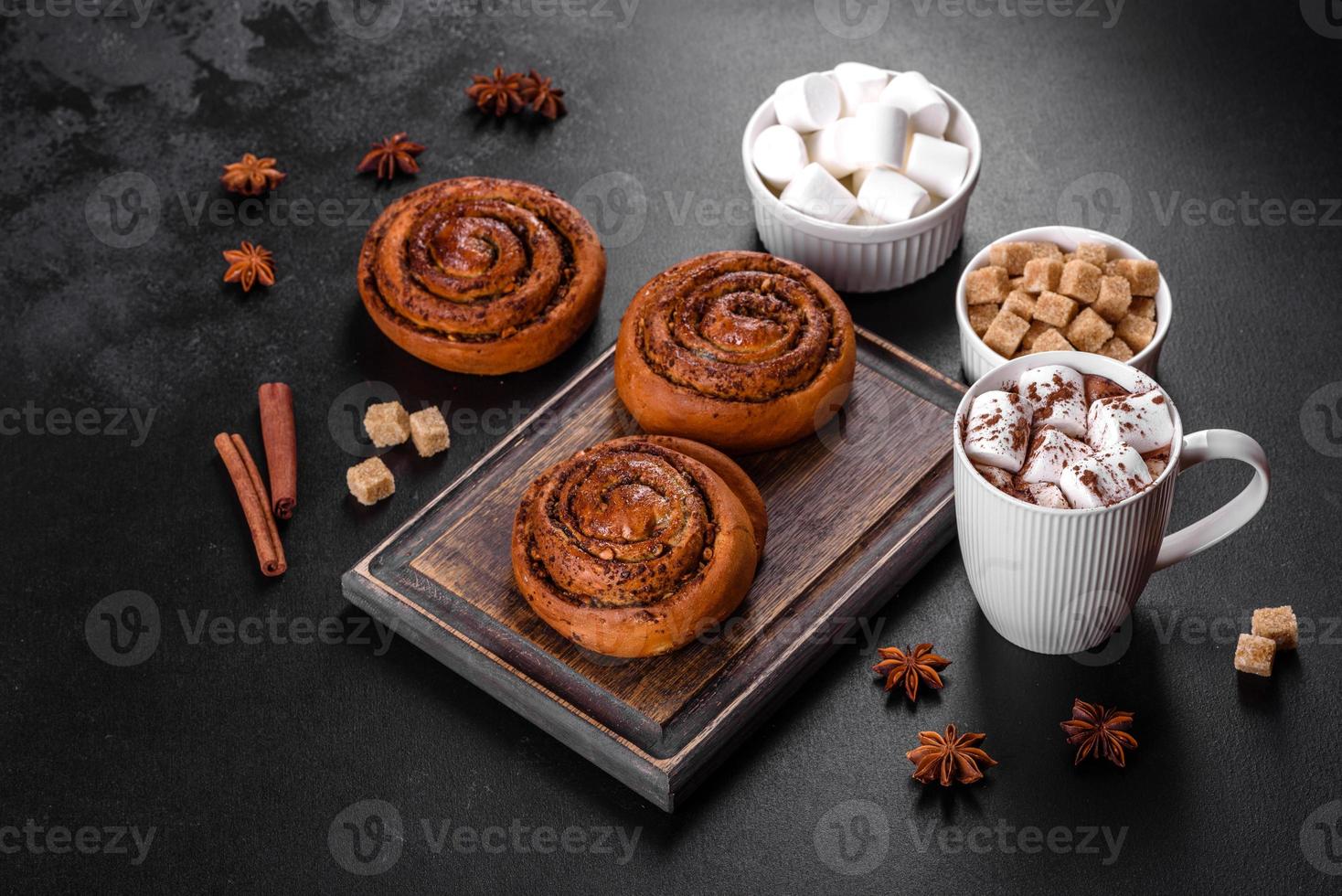 Freshly baked cinnamon roll with spices and cocoa filling on a black background photo