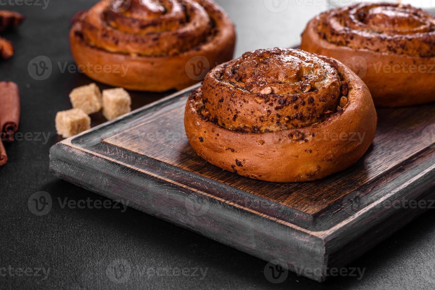 Freshly baked cinnamon roll with spices and cocoa filling on a black background photo