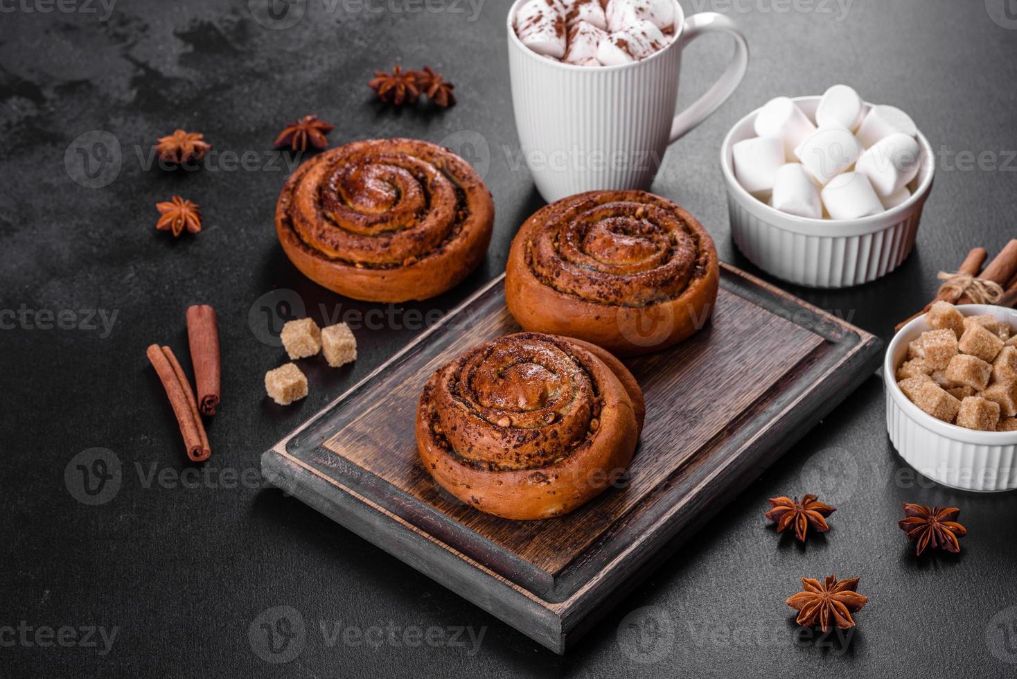Freshly baked cinnamon roll with spices and cocoa filling on a black background photo