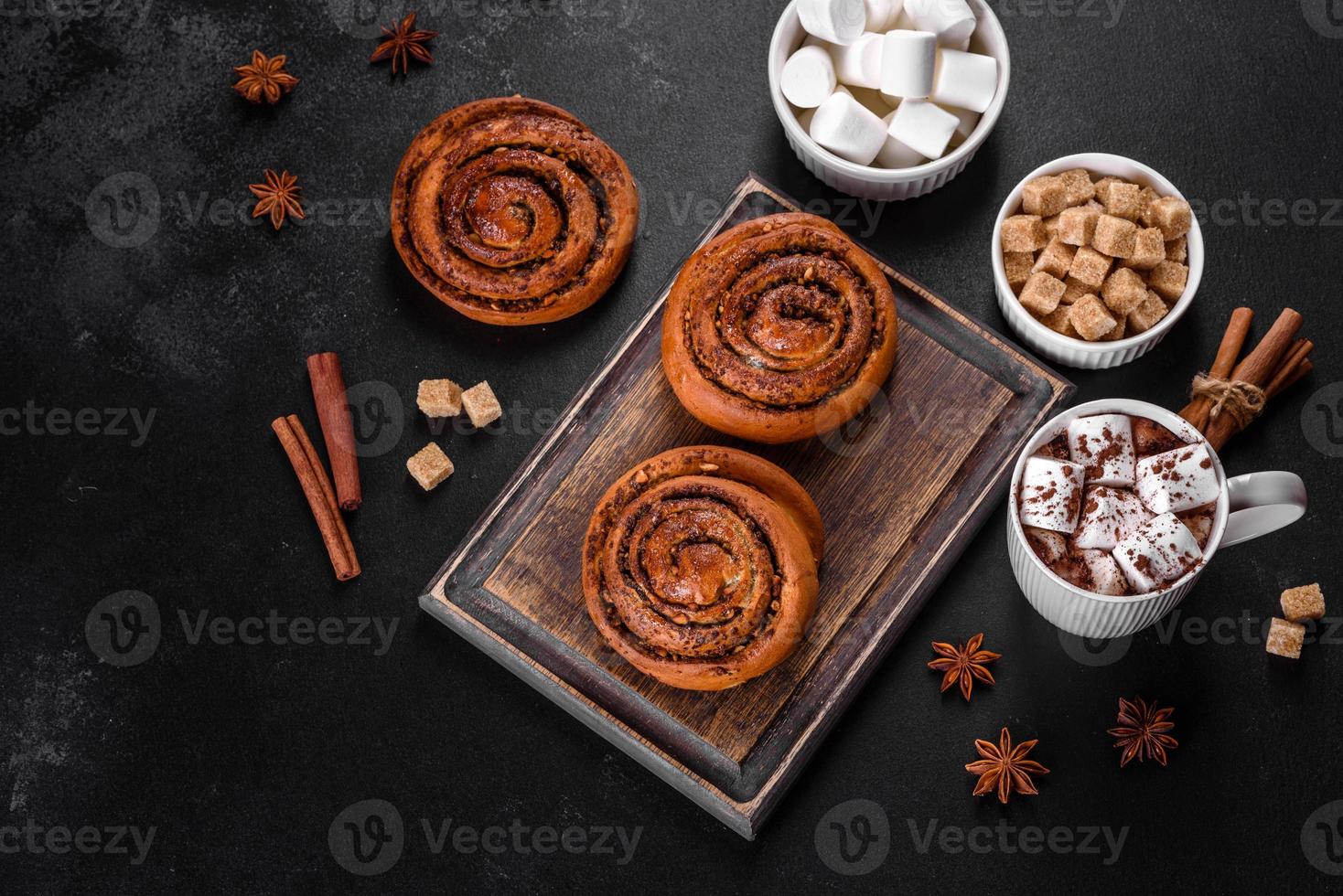 Freshly baked cinnamon roll with spices and cocoa filling on a black background photo