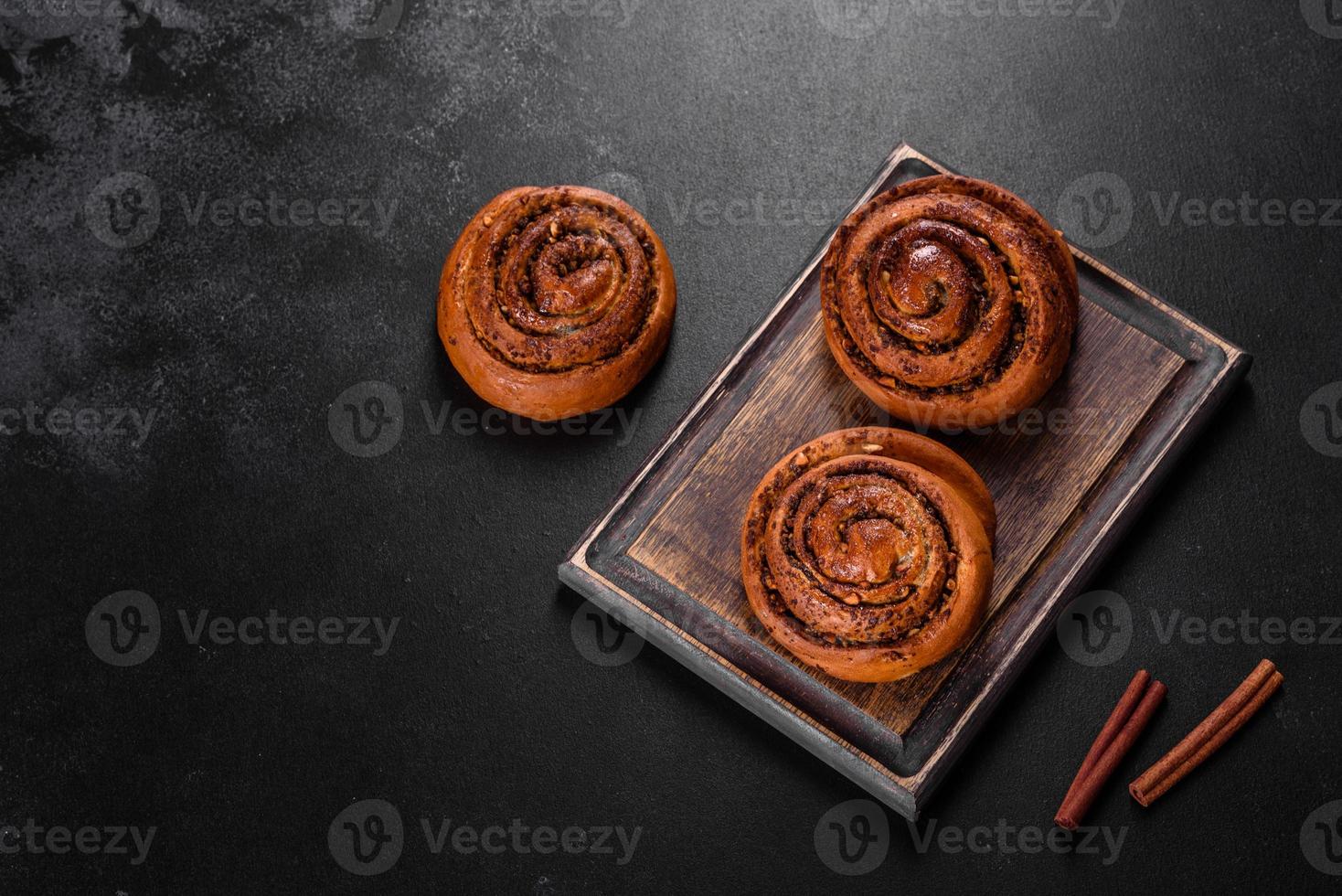 Freshly baked cinnamon roll with spices and cocoa filling on a black background photo