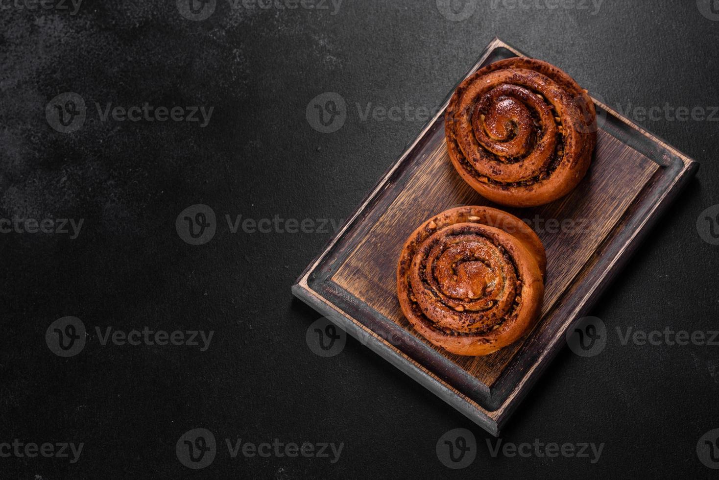 Freshly baked cinnamon roll with spices and cocoa filling on a black background photo