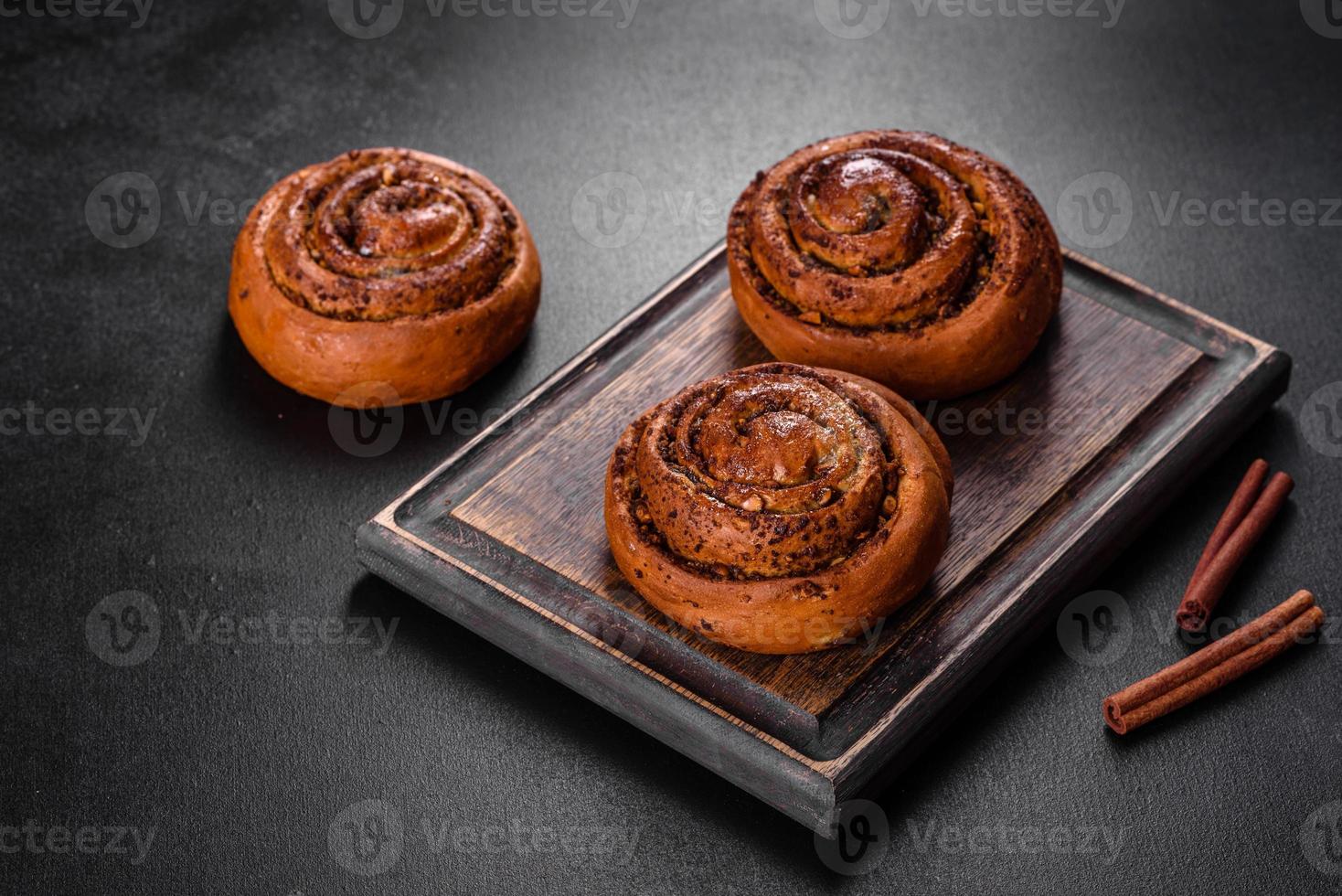 Freshly baked cinnamon roll with spices and cocoa filling on a black background photo