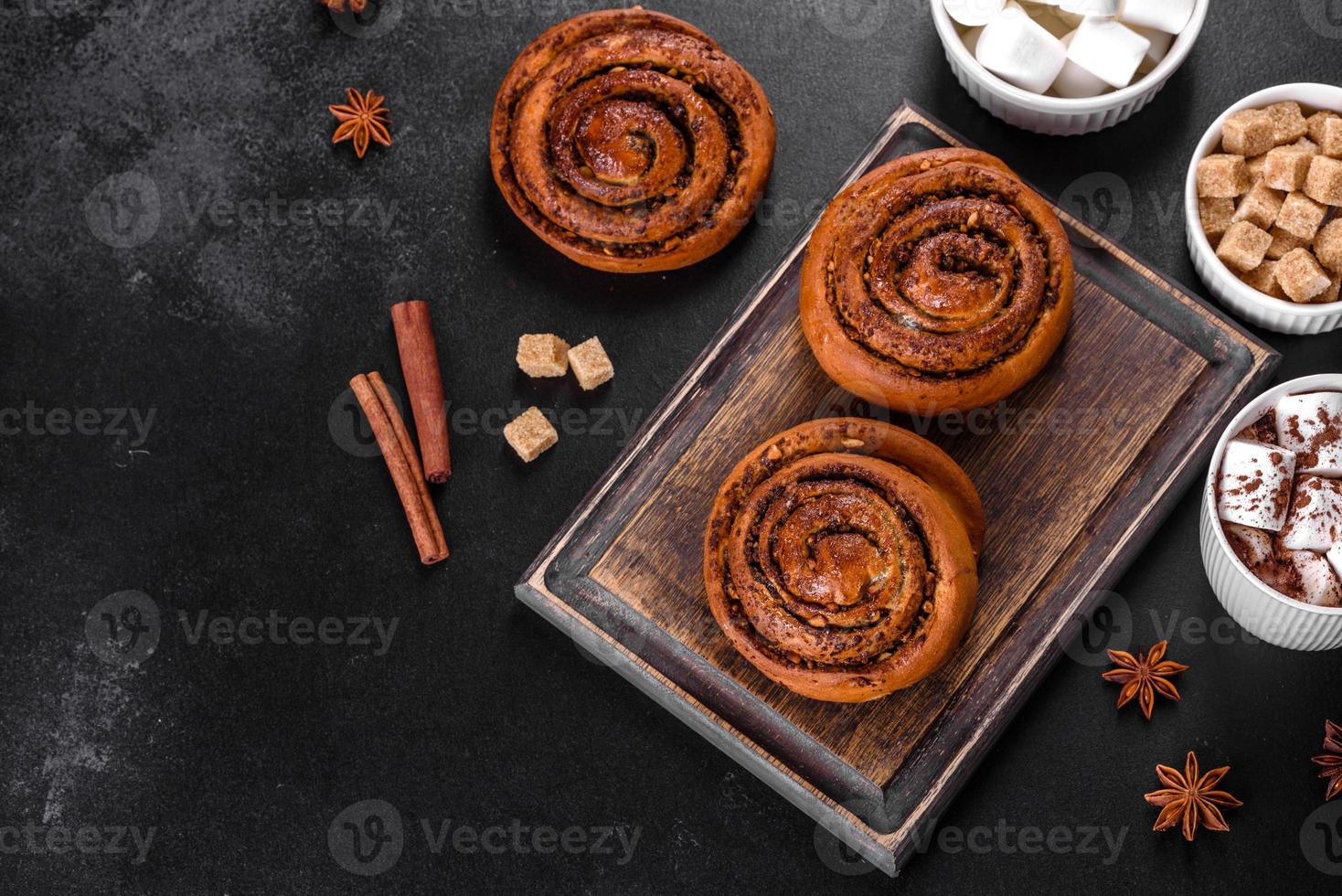 Rollo de canela recién horneado con especias y relleno de cacao sobre un fondo negro foto