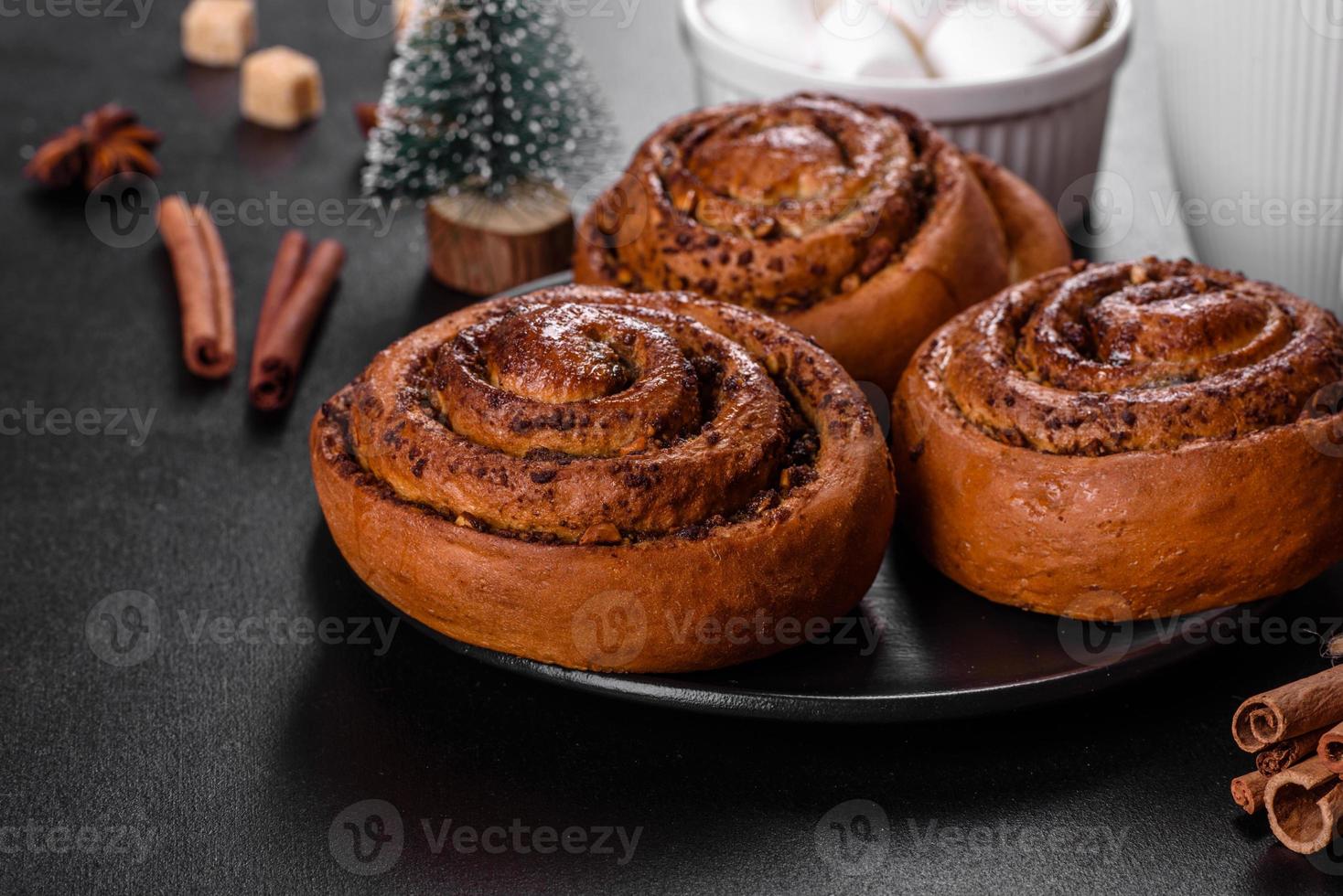 Freshly baked cinnamon roll with spices and cocoa filling on a black background photo