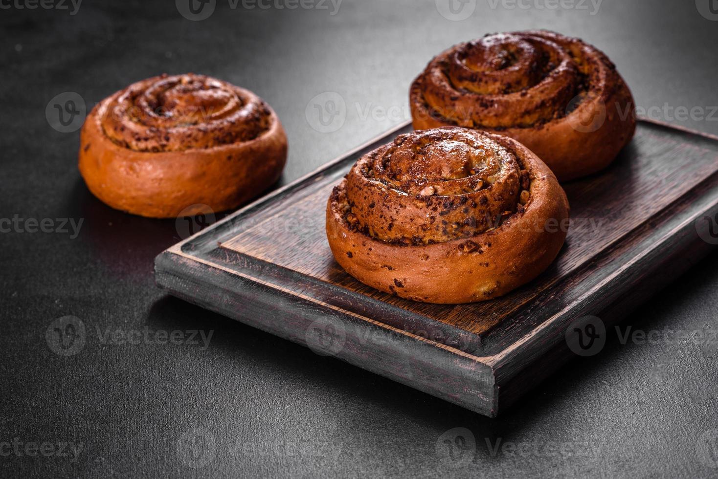 Freshly baked cinnamon roll with spices and cocoa filling on a black background photo