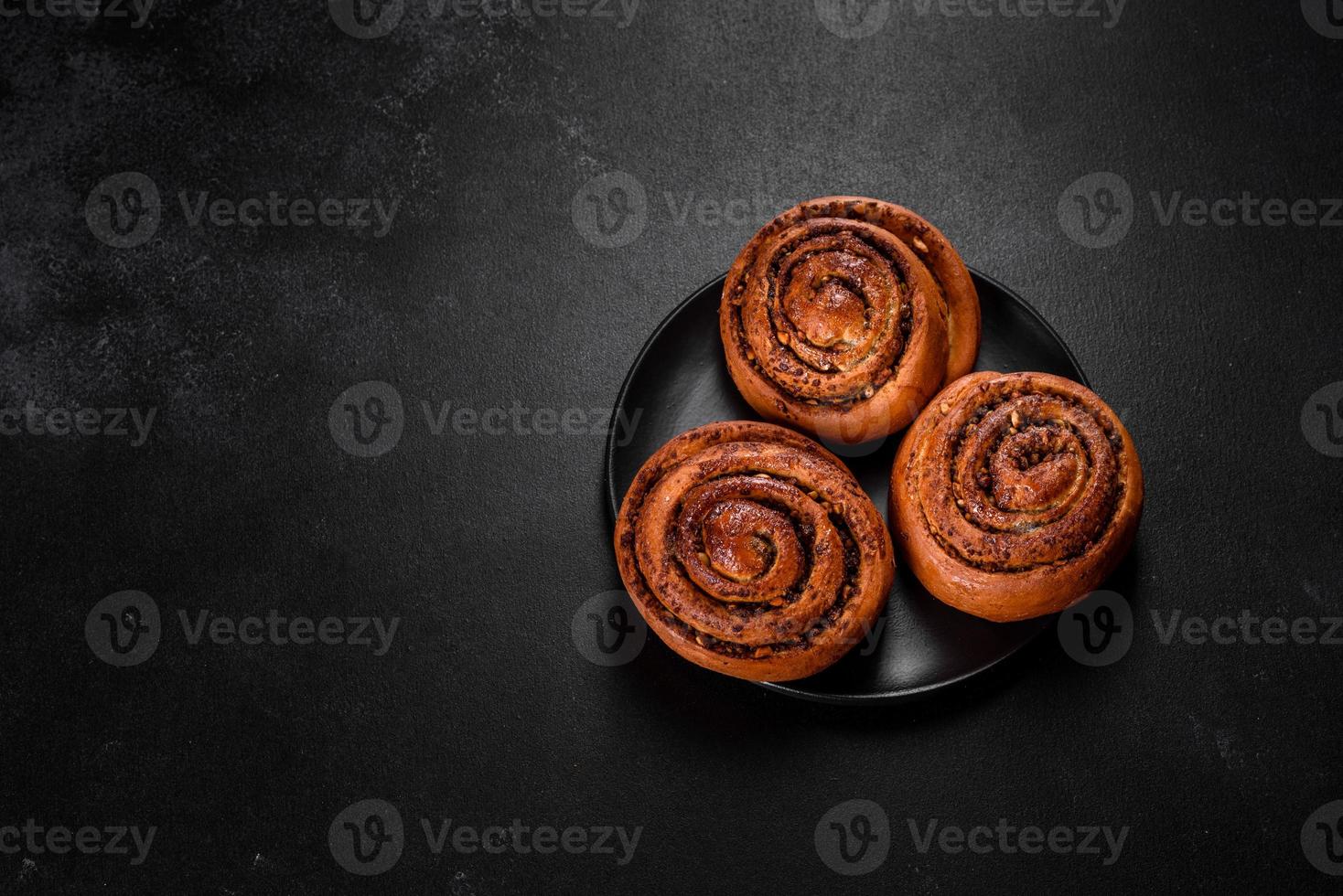 Freshly baked cinnamon roll with spices and cocoa filling on a black background photo