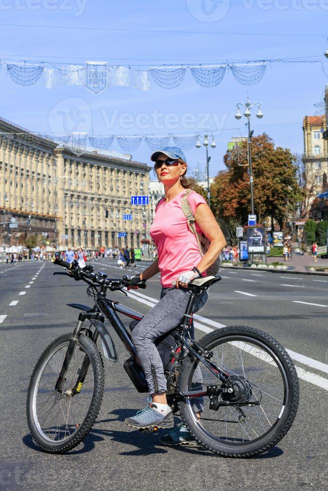 una joven en una bicicleta eléctrica de montaña se encuentra en la carretera de la calle khreschatyk en kyiv. foto