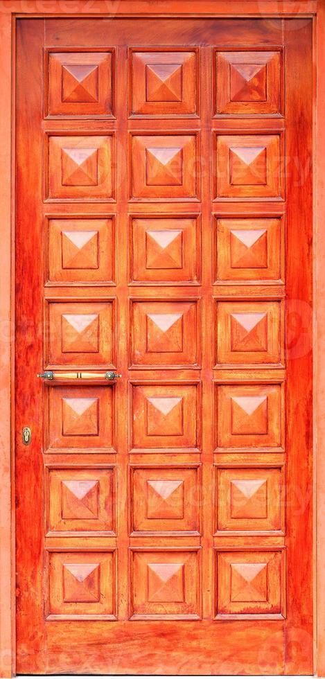 Old orange wooden entrance doors with a bronze handle and symmetrical square panels in Greek style. photo