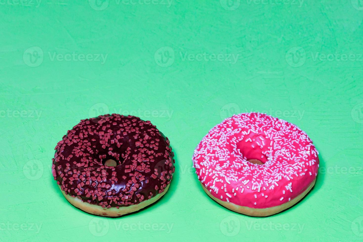 Delicious chocolate and cream donuts on a light green rough surface. photo