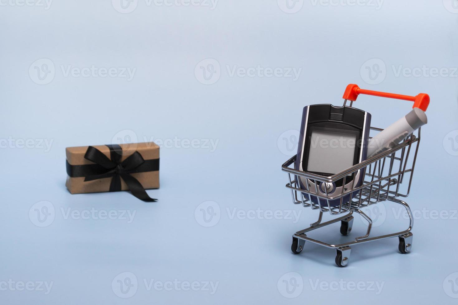 cesta con glucómetro sobre un fondo de color con retroiluminación. concepto navideño de compras en línea, farmacias y ventas más regalo. de cerca, copie el espacio foto