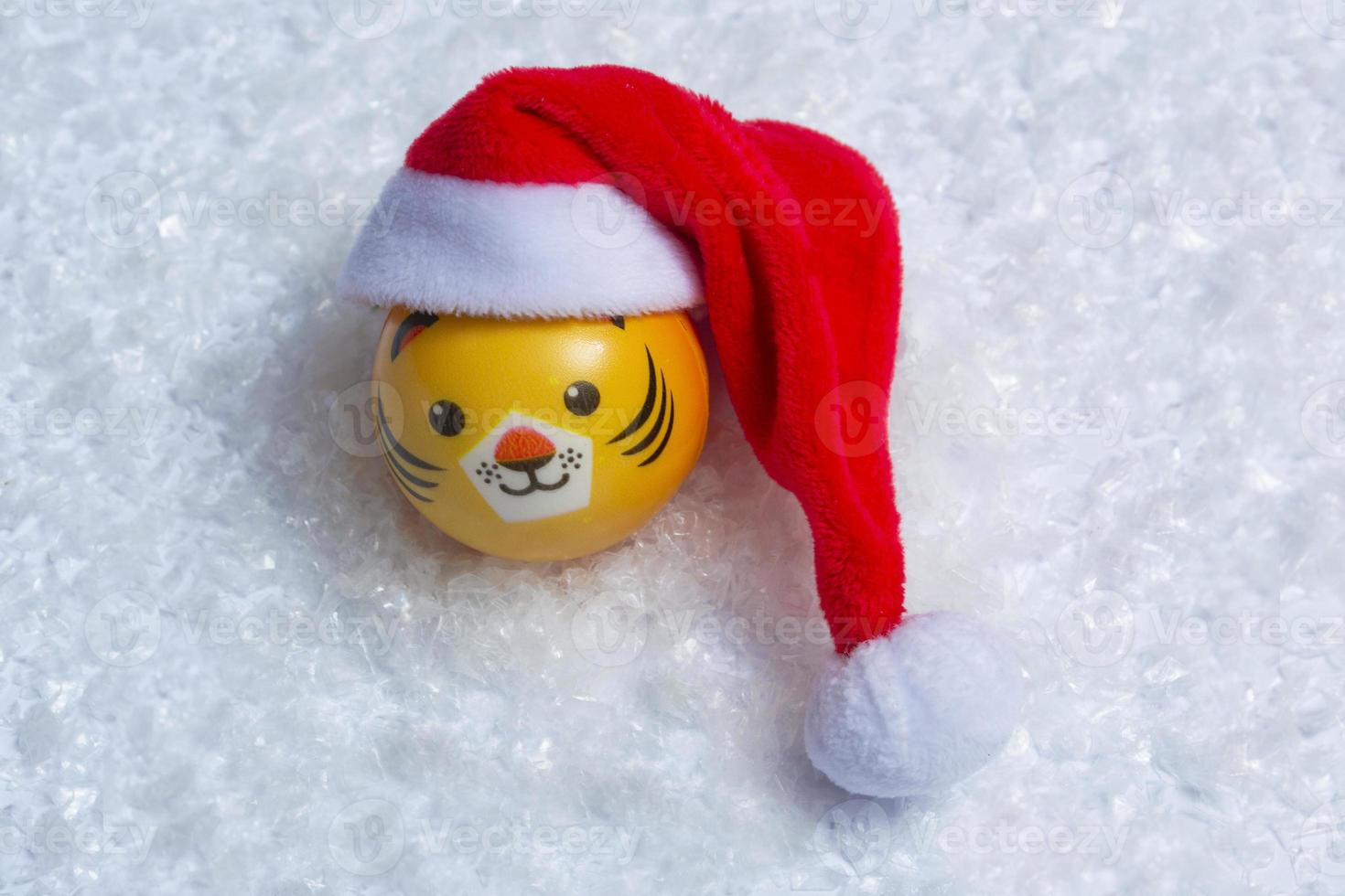 The symbol of the New Year's tiger in a Santa hat in the snow on a background of bokeh lights. New year concept photo