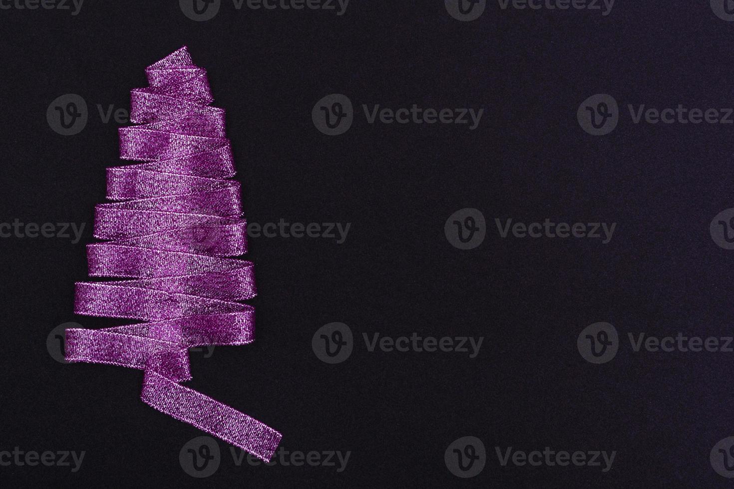 Christmas concept. Purple Christmas tree made of ribbons on a black background. With copy space Template for postcards, packaging. photo