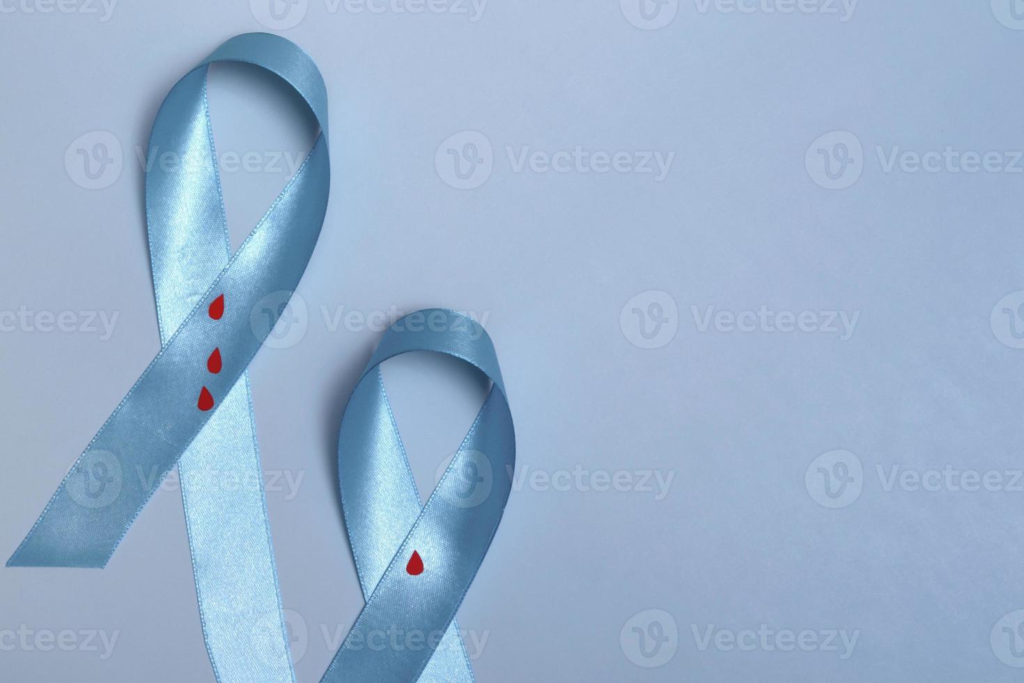 Close up top view of concept for World Diabetes Day 14 November. Blue ribbon with drops of blood on a blue background. photo