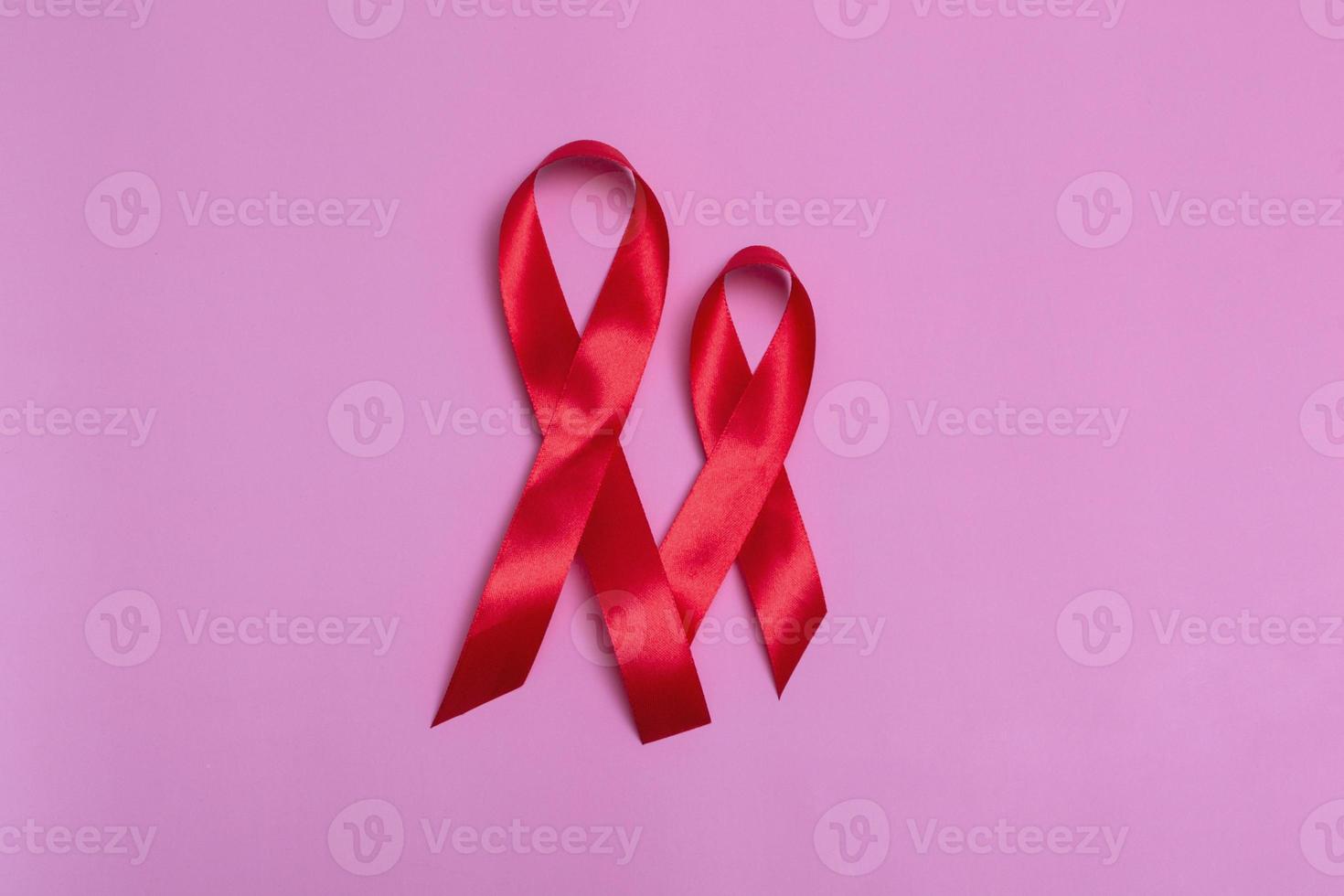 Top view on pink background with red ribbon concept December 1st International AIDS Day close-up. photo