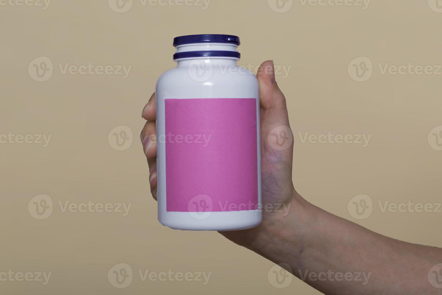 close-up, on a beige background. the girl holds vitamins in a white bottle in her hand. vitamins for immunity, recovery. vitamins for beauty. space for text photo