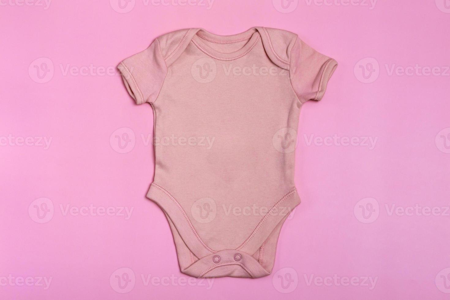 Pink blank baby bodysuit template, mock up close-up on pink background. Baby bodysuit, jumpsuit for newborns. View from above photo