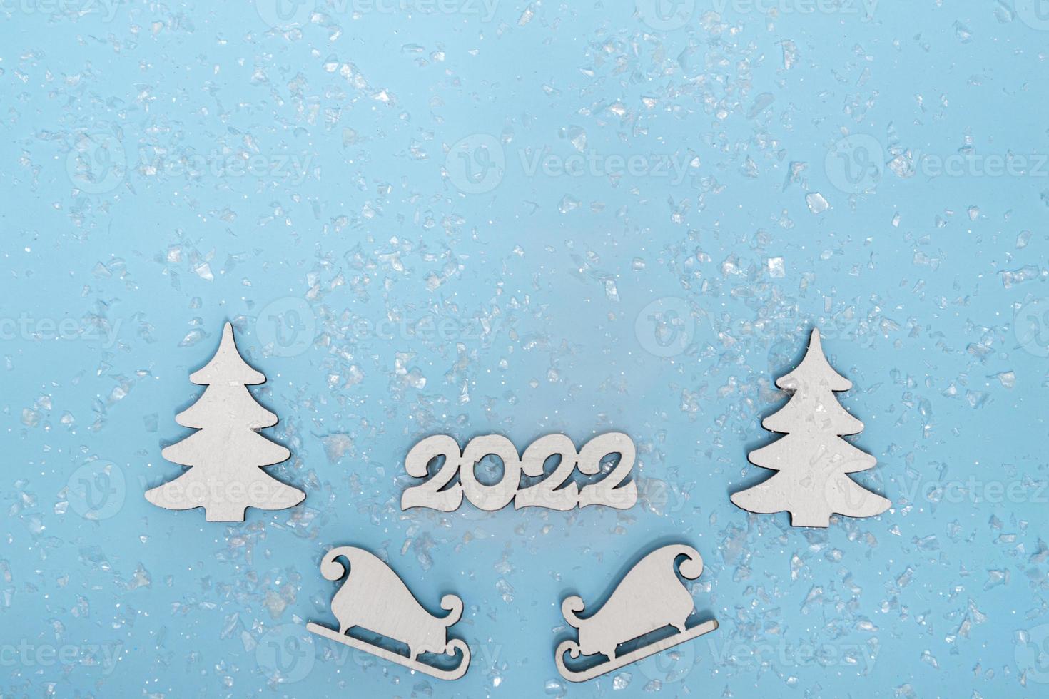 feliz navidad y próspero año nuevo banner. cartel festivo con un árbol de Navidad, trineos y nieve sobre un fondo azul. año nuevo 2022 espacio de copia de cerca foto