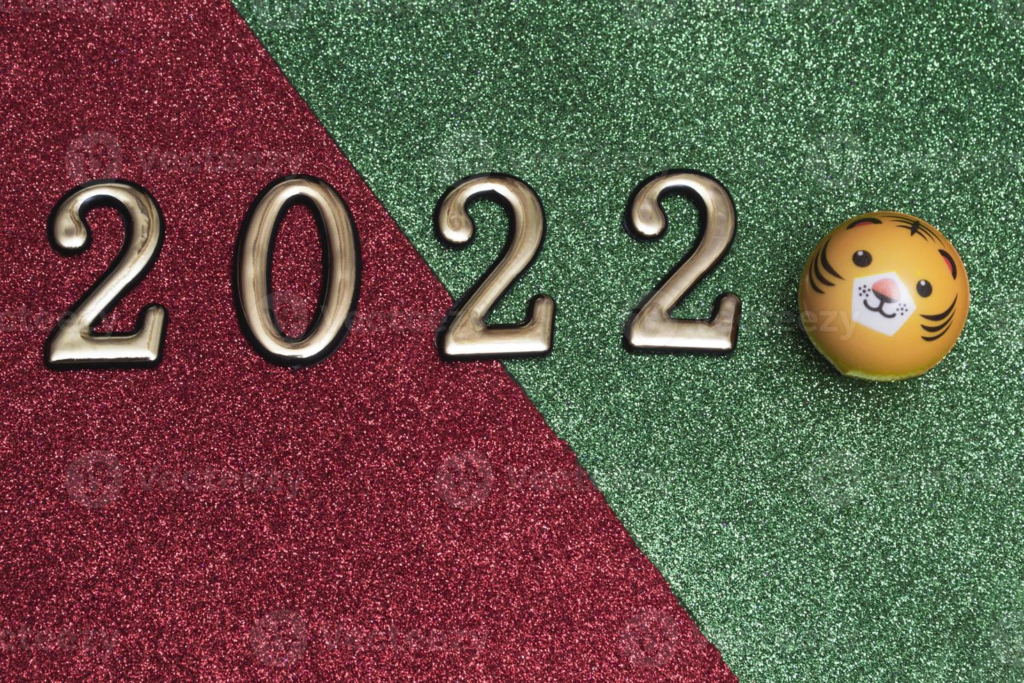 New year concept golden numbers 2022 with tiger face on green-red glitter background with copy space photo